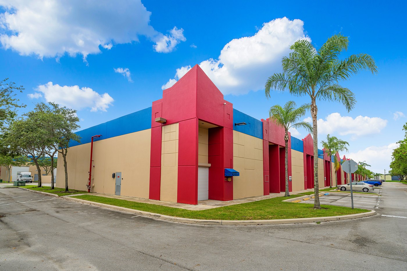 Corner of a Cortland Commercial Center II building with a red entry tower and palm trees