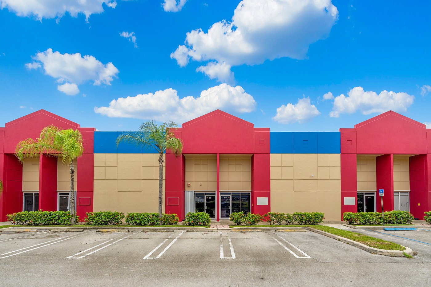 Front of a Cortland Commercial Center II building with three red entry towers and palm trees