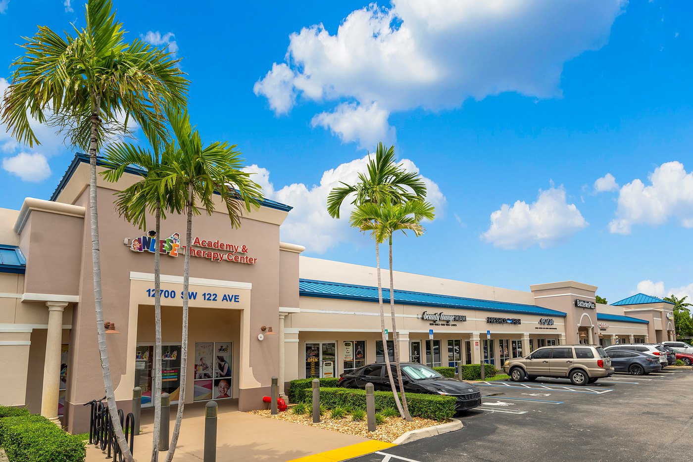 Storefronts at Cortland Commercial Plaza with palm trees and the 12700 SW 122 Ave entrance