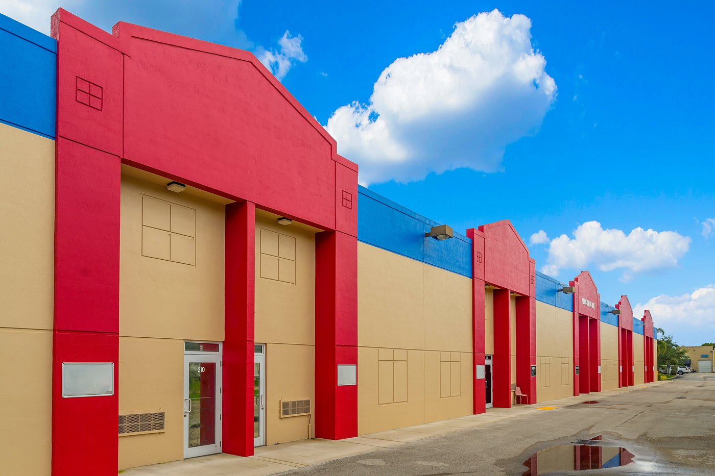 Close view of red entry towers under a blue parapet at Zacarias Commercial Center II