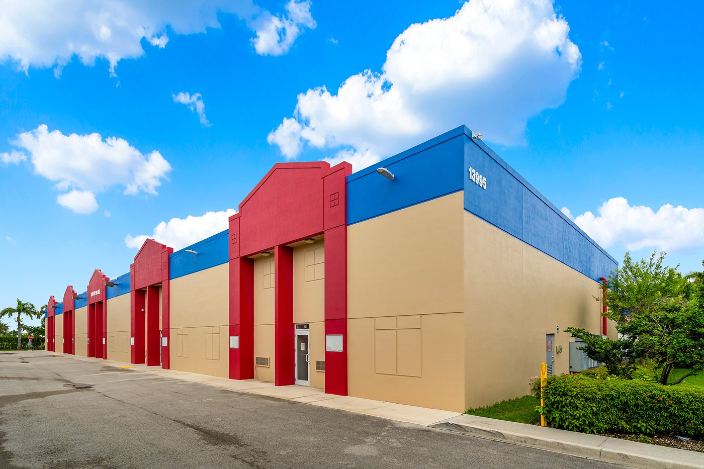 Corner of the 13995 building, its number on the blue parapet, with red entry towers along the row, Zacarias Commercial Center II