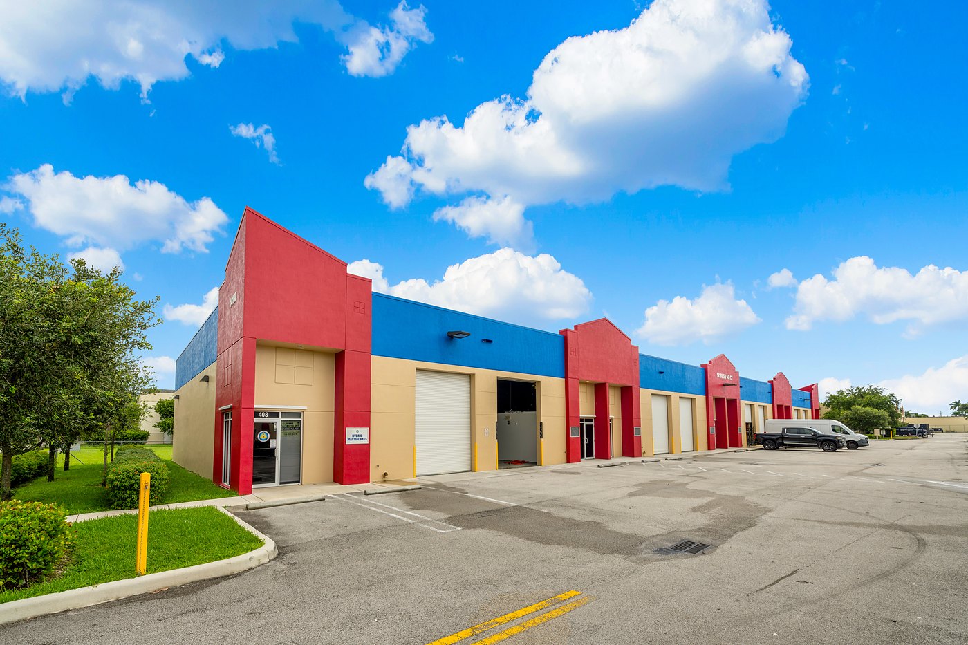 Industrial / flex row with red entry towers, a blue parapet and roll-up doors, Zacarias Commercial Center III