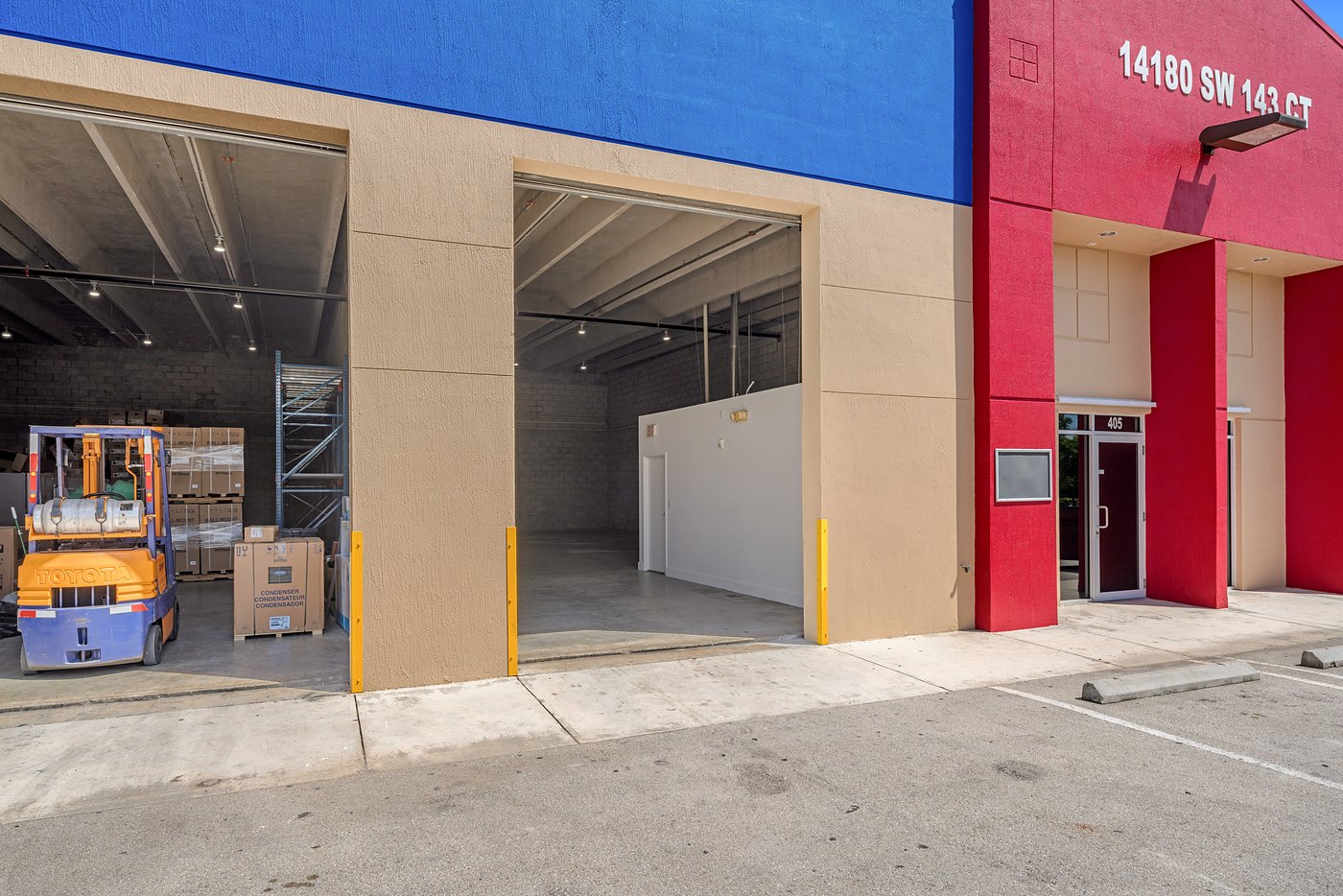 Open roll-up doors and a forklift beside the 14180 SW 143rd Court entry tower, Zacarias Commercial Center III