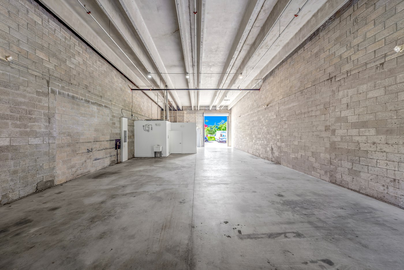 Empty warehouse bay with block walls and daylight at the roll-up door, Zacarias Commercial Center III