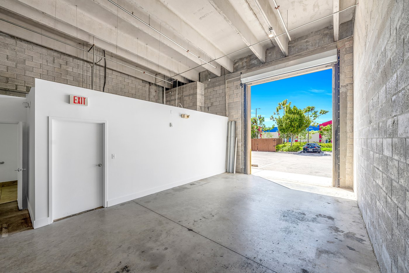 Warehouse interior with an open roll-up door and a white build-out wall, Zacarias Commercial Center III