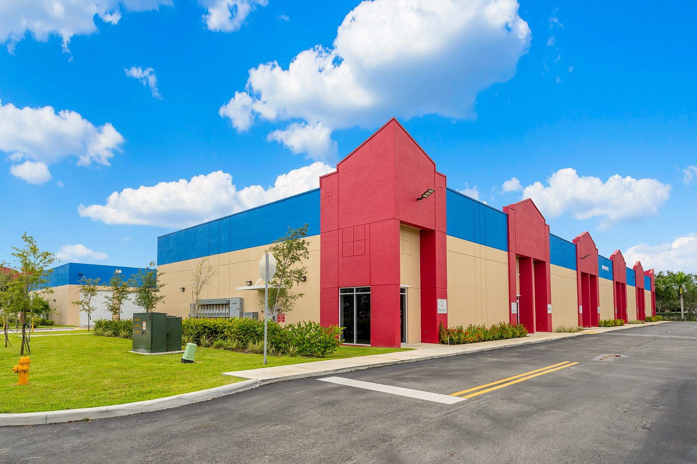 Pointed red entry towers along a tan building with a blue parapet, Zacarias Commercial Center IV