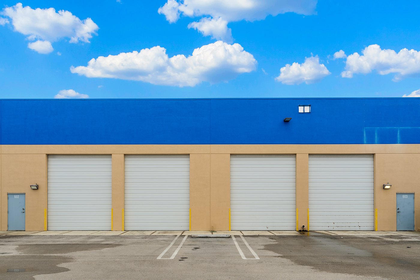 Four roll-up loading doors under a blue parapet, Zacarias Commercial Center IV