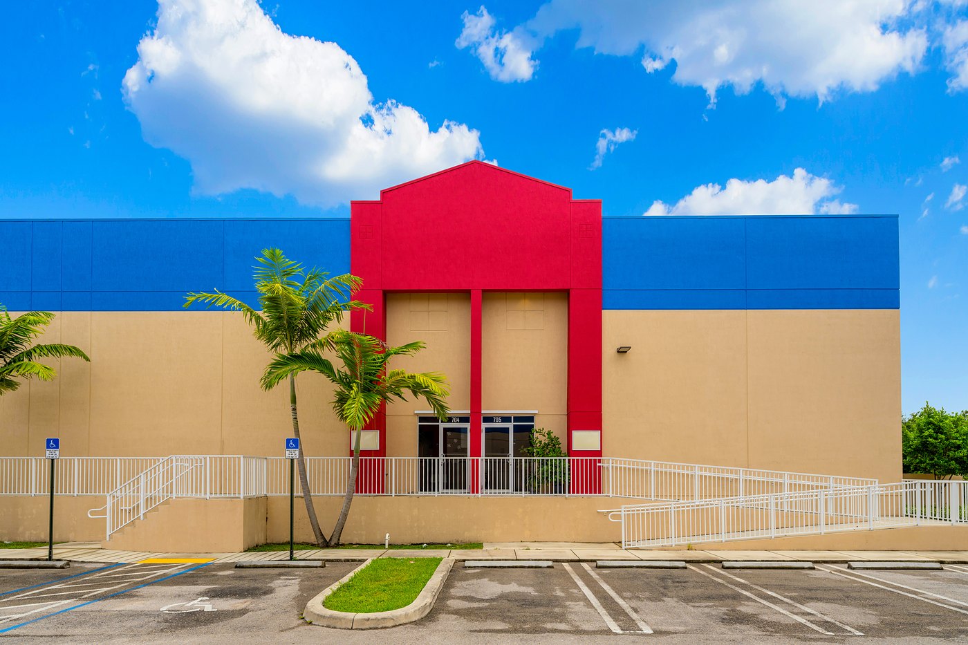 Front elevation with a red entry tower, palm trees and an accessible ramp, Zacarias Commercial Center IV