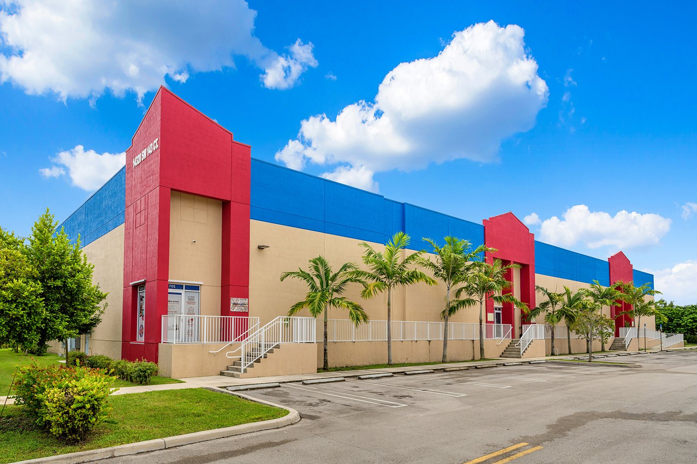 Red entry tower, blue parapet and palm-lined walkway on SW 143rd Court, Zacarias Commercial Center IV
